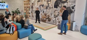 Trenerzy opowiadają o znanych osobach zamieszczonych na ściance w Centrum Edukacyjnym SMWI – 