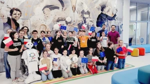 Dzieci stoją na ściance z flagami Unii Europejskiej –