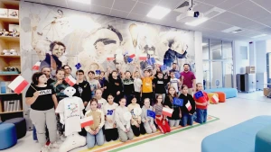 Dzieci stoją na ściance z flagami Unii Europejskiej –