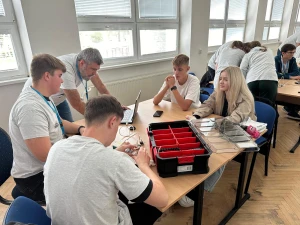 Młodzież siedzi przy stoliku programując klocki Lego MIndstorm –