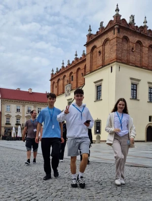Grupa młodzieży stoi na tle tarnowskiego Ratusza –