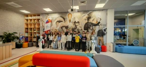 Uczniowie stoją na tle ścianki ze słynnymi wynalazcami i twórcami postępu – 