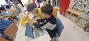 Uczniowie siedzą w ławkach i uczą się programowania z użyciem klocków LEGO SPIKE – 