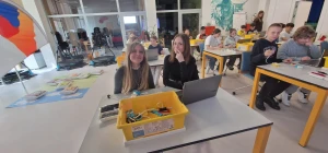 Uczniowie siedzą w ławkach i uczą się programowania z użyciem klocków LEGO SPIKE – 